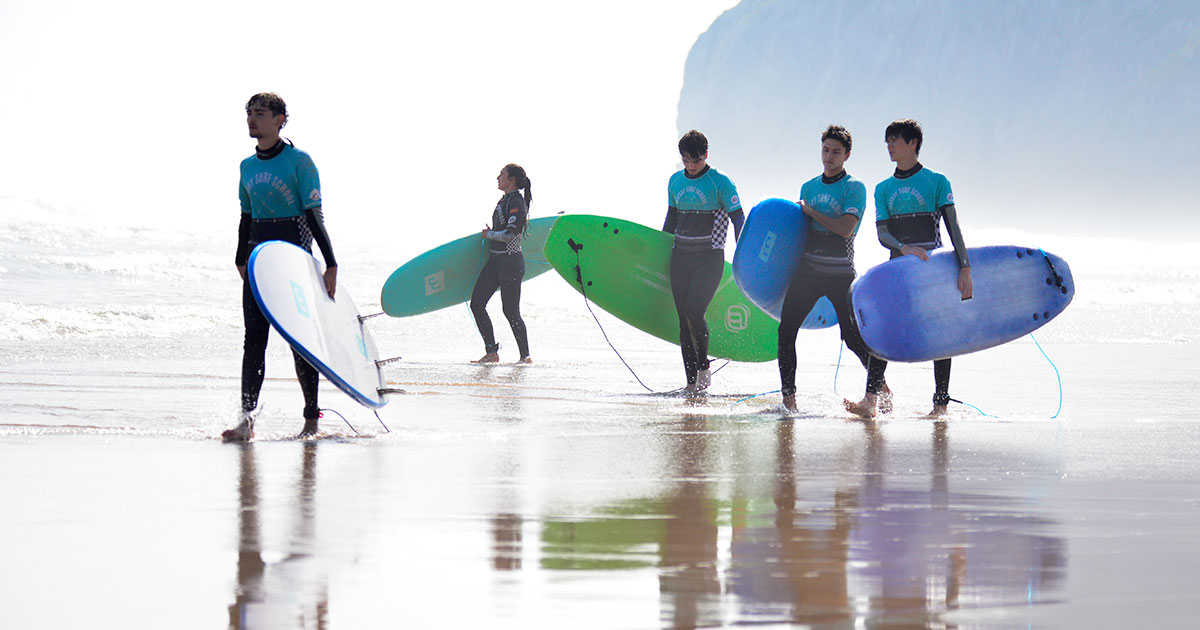 Adolescentes disfrutando de una sesión de surf la playa de Berria